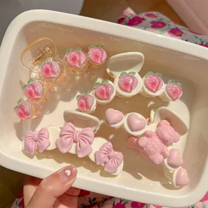 Pink and white hair claws set featuring peach, bow, and bear designs on soft fabric