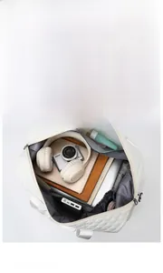 Macro view of white quilted travel bag interior showing large capacity for gadgets