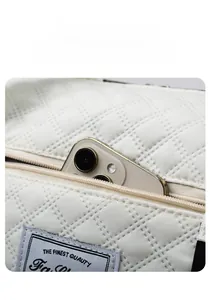 Detailed macro view of the front zipper pocket on white quilted bag holding a smartphone