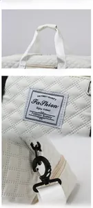 Close-up of white quilted travel bag showing diamond stitching and metal swivel hooks