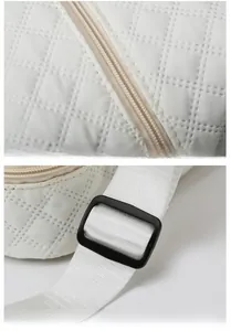Detailed macro view of white quilted fabric, smooth zipper, and adjustable shoulder strap