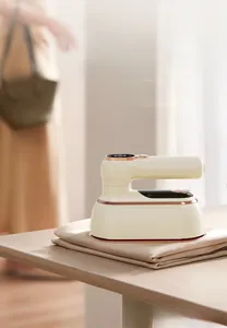 Close-up of portable steam iron with digital display and rose gold trim on wood table