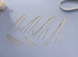 Detail of gold minimalist U-shaped multi-strand box chain threader earrings on a blue base