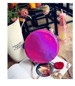 Macro shot of circular laser holographic crossbody bag with purple gradient on a magazine