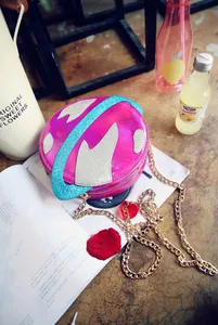 Macro shot of fuchsia laser crossbody bag with sequined planet rings and gold chain