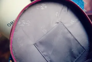 Detail view of round bag interior with floral grey lining and inner open pocket