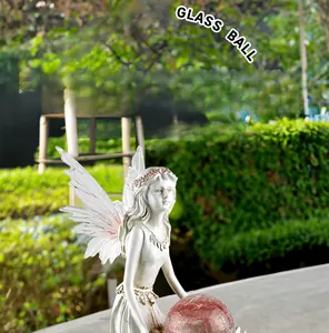 Detail of flower fairy statue holding a pink glass ball for outdoor garden decor