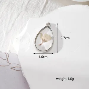 Vue macro d'un pendentif en résine avec fleur séchée mesurant 2,7 cm sur 1,6 cm