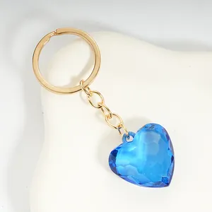 Close-up of blue faceted acrylic heart keychain with gold metal ring on white background