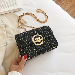 Detail of black tweed crossbody bag with golden chain and round metal turn-lock