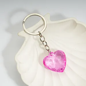 Pink heart-shaped acrylic crystal keychain displayed in a white shell-shaped tray