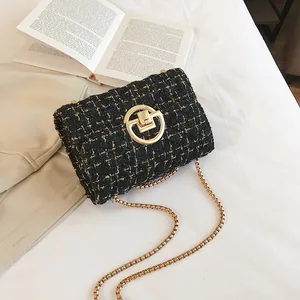 Close-up of black tweed crossbody bag with gold chain strap on a minimalist background