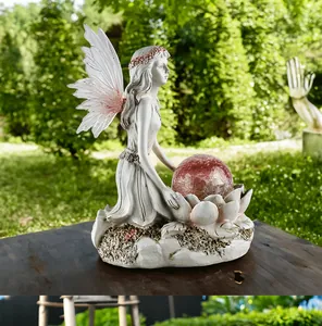 Detail of flower fairy garden statue holding a red cracked solar glass ball on lotus base