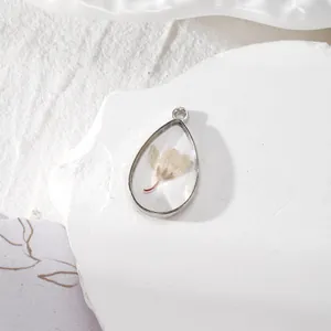 Vue détaillée du pendentif goutte en résine avec fleurs séchées jaunes et cadre en argent