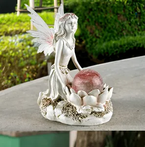 Detail of flower fairy sculpture holding a pink cracked glass solar ball in the garden