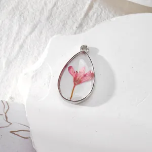 Gros plan détaillé d'un pendentif en résine en forme de larme avec fleur rose et argent