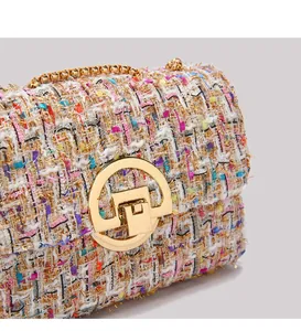 Close-up of multicolor tweed weave texture and golden circular metal twist lock on a chain bag