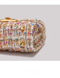 Detail view of colorful tweed fabric and golden protective metal feet on handbag base