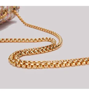 Close-up of golden box chain strap and colorful tweed fabric on a stylish shoulder bag