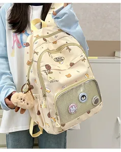 Close-up of a cute beige student backpack with transparent pocket and plush bear charm