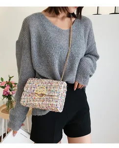Close-up of colorful tweed crossbody bag with gold chain strap and rotary metal lock