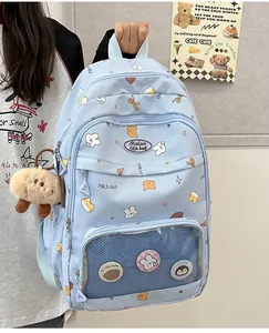 Detail view of light blue canvas backpack with clear pocket, pins and plush sheep pendant