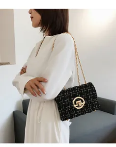 Detail of black tweed crossbody bag with gold chain strap and metallic circular clasp