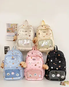 Row of five colorful school backpacks with transparent windows and plush charms for girls