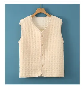 Close-up of beige quilted thermal vest with V-neck and button closure on wooden hanger