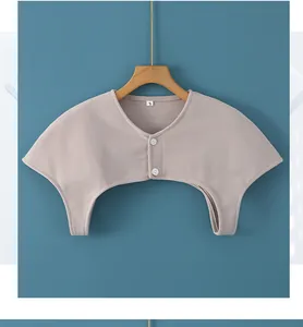 Detail of soft beige knit shoulder warmer with white buttons and size L label