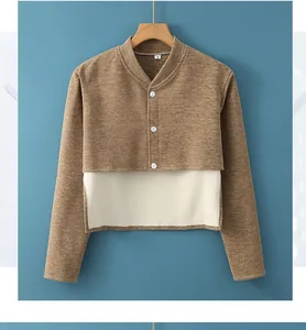 Detalle de la chaqueta de punto marrón con botones blancos y dobladillo crema en capas