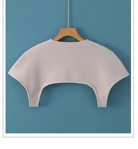 Close-up of pink knit shoulder warmer shawl on a wooden hanger with blue background