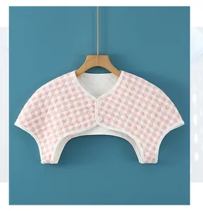 Detail of pink plaid quilted shoulder warmer with white buttons on a wooden hanger