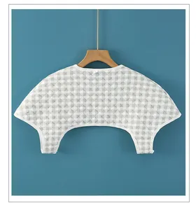 Close-up of gray checkered quilted cotton shoulder warmer with white piped edges on hanger
