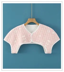 Detail of pink quilted shoulder warmer with white cartoon puppy print and dual buttons