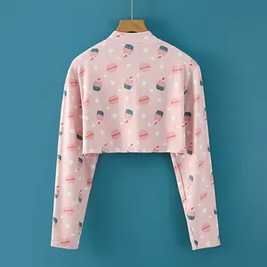 Cárdigan corto rosa con estampados de postres dulces en percha sobre fondo azul