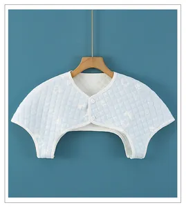 Detailed view of light blue quilted shoulder warmer with diamond stitching and soft buttons