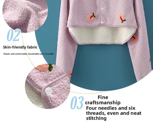 Dettaglio dello scaldaspalle rosa con ricamo a pesca e fodera in peluche bianco