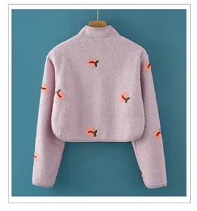 Close-up of pink fleece shoulder warmer with peach patterns on a wooden hanger
