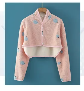 Dettaglio della mantella in pile rosa con pois blu e bottoni bianchi per il collo