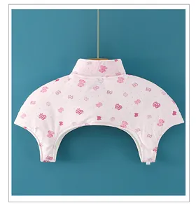 Detail of light pink shoulder warmer with bow print and button closure on blue background