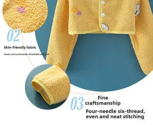 Detail der gelben Fleece-Schulterwärmer für Babys mit weißen Knöpfen und Stickerei