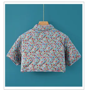 Detail of blue floral quilted shoulder warmer showing diamond stitching and fabric texture