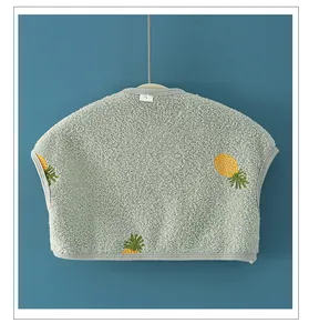 Detail of baby plush shoulder warmer vest with yellow pineapple pattern and soft texture