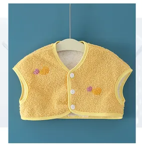 Close-up of ginger yellow plush baby vest featuring heart embroidery and white buttons