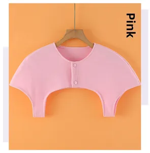 Detail of pink cotton shoulder wrap with two-button closure on a wooden hanger