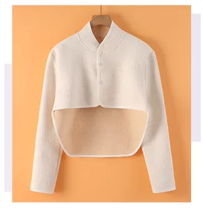 Detail of beige shoulder warmer with embossed bear patterns and snap button closure