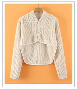 Close-up of white fleece shoulder warmer with three buttons against orange backdrop