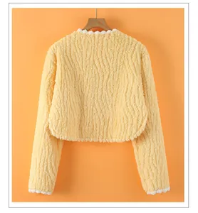 Detail of soft yellow plush shoulder warmer with white wavy trim and furry texture