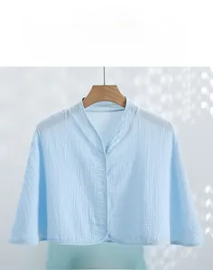 Detail of light blue double-layer cotton gauze shoulder shawl with button closure